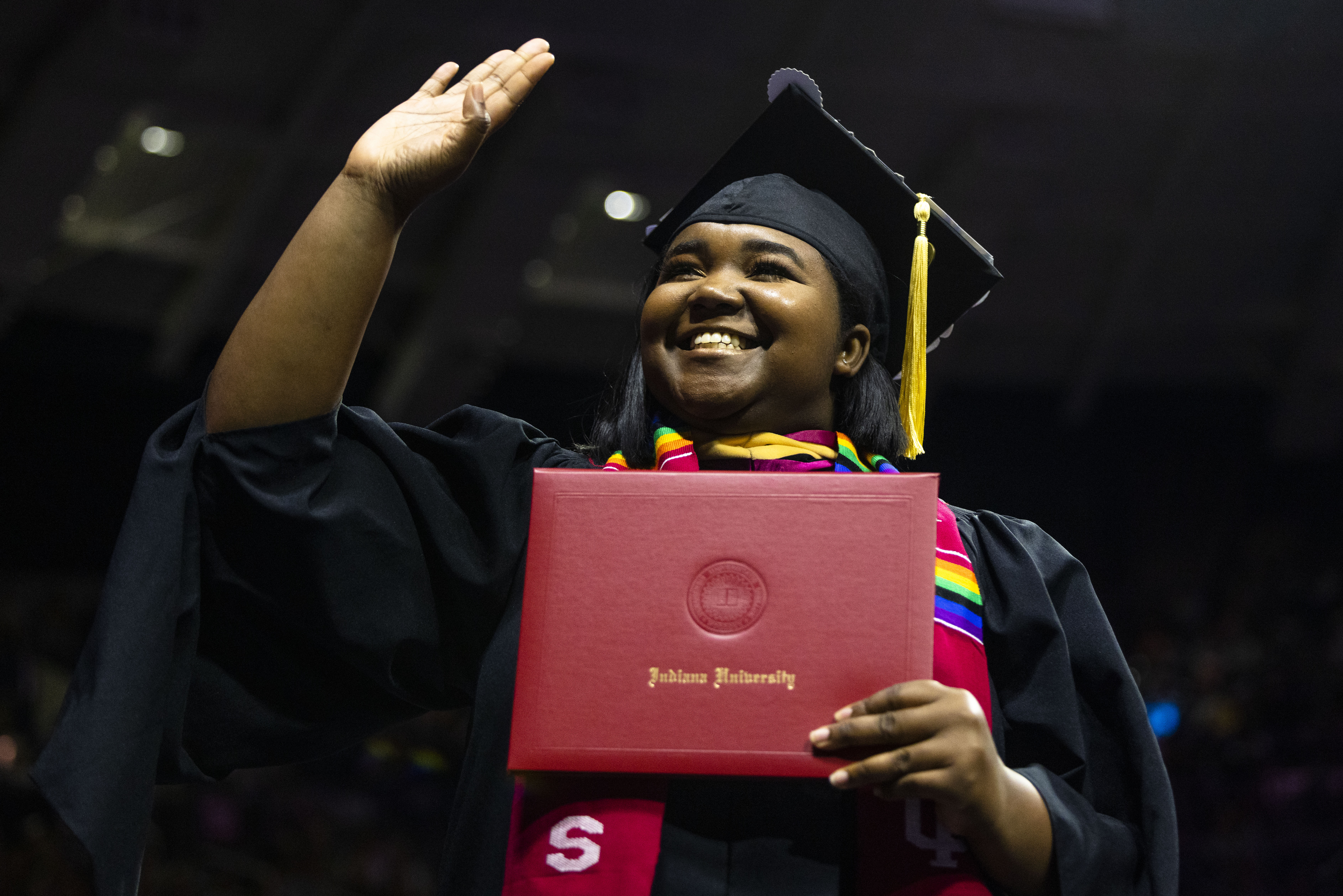 A 2023 IU South Bend graduate waves to the audience during Commencement.